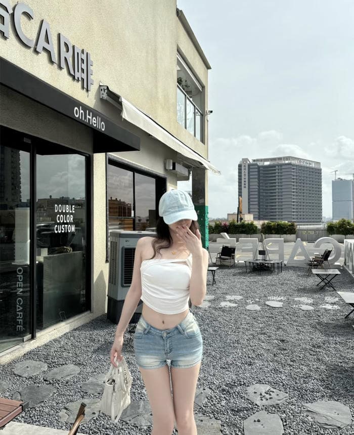 Hình ảnh gái xinh mặc quần ngắn đứng cạnh quán cà phê